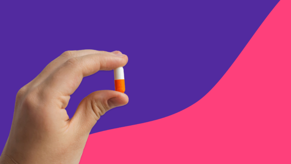 Hand holding a white and orange antibiotic capsule: Can amoxicillin be used for acne?